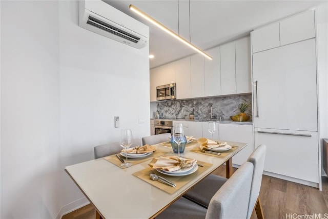 dining room featuring a wall mounted air conditioner, sink, and dark wood-type flooring