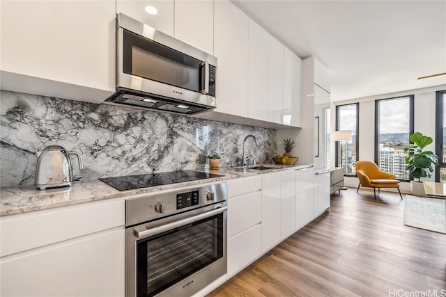 kitchen featuring light wood-type flooring, white cabinetry, sink, and appliances with stainless steel finishes