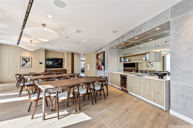 dining space with wine cooler, light hardwood / wood-style flooring, and sink