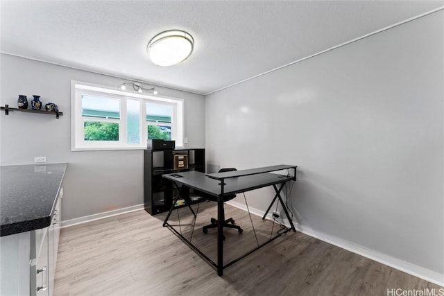 office with light hardwood / wood-style floors and a textured ceiling