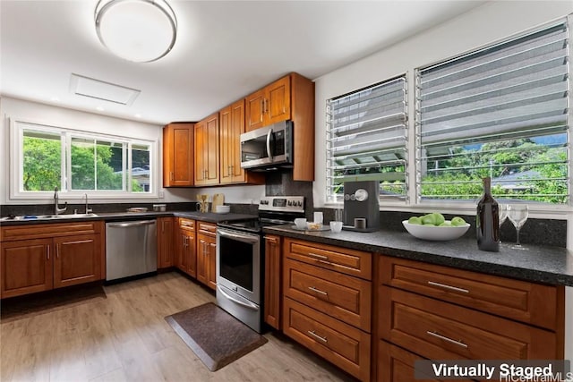 kitchen featuring decorative backsplash, light wood-type flooring, stainless steel appliances, and sink