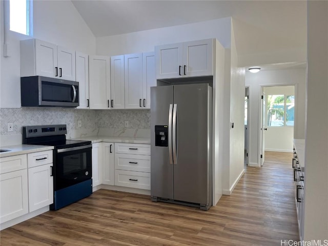 kitchen featuring lofted ceiling, appliances with stainless steel finishes, and white cabinets