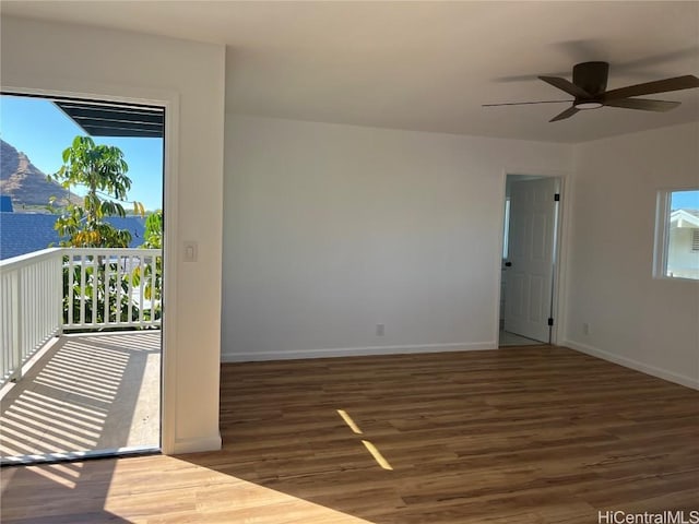 unfurnished room with dark hardwood / wood-style flooring, a mountain view, a wealth of natural light, and ceiling fan