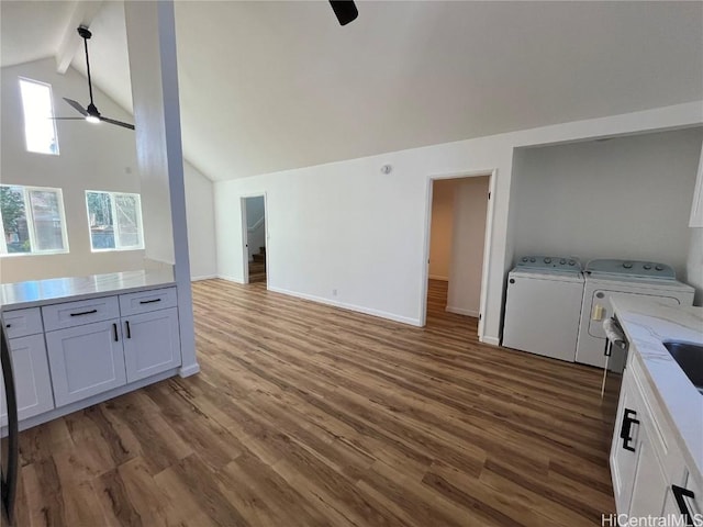 unfurnished living room with lofted ceiling with beams, dark hardwood / wood-style flooring, independent washer and dryer, and ceiling fan