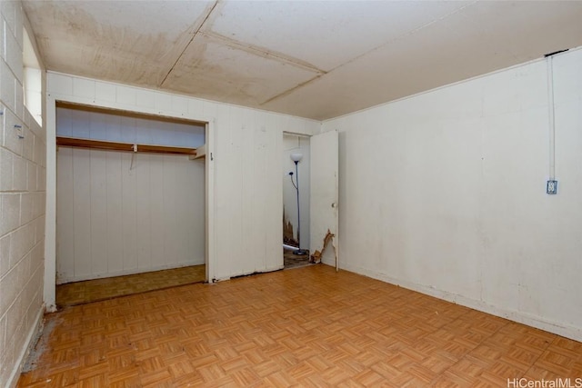 unfurnished bedroom featuring light parquet floors and wooden walls