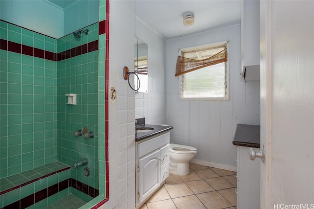 bathroom featuring a tile shower, tile patterned flooring, vanity, and toilet