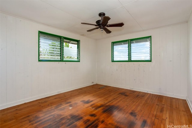 unfurnished room featuring ceiling fan, wooden walls, and wood-type flooring