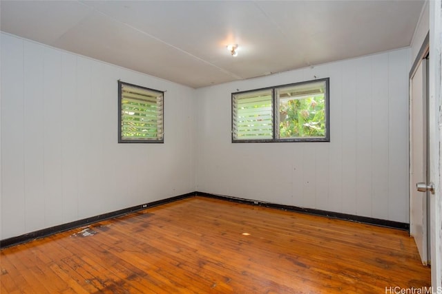 unfurnished room featuring hardwood / wood-style flooring and wooden walls