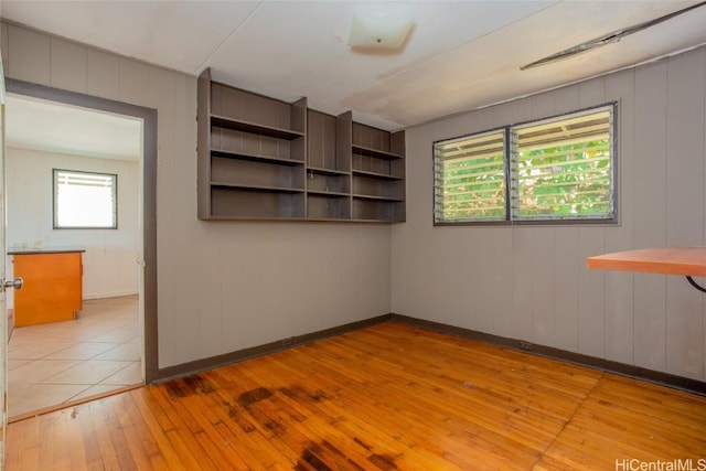 empty room with wood walls and light hardwood / wood-style floors