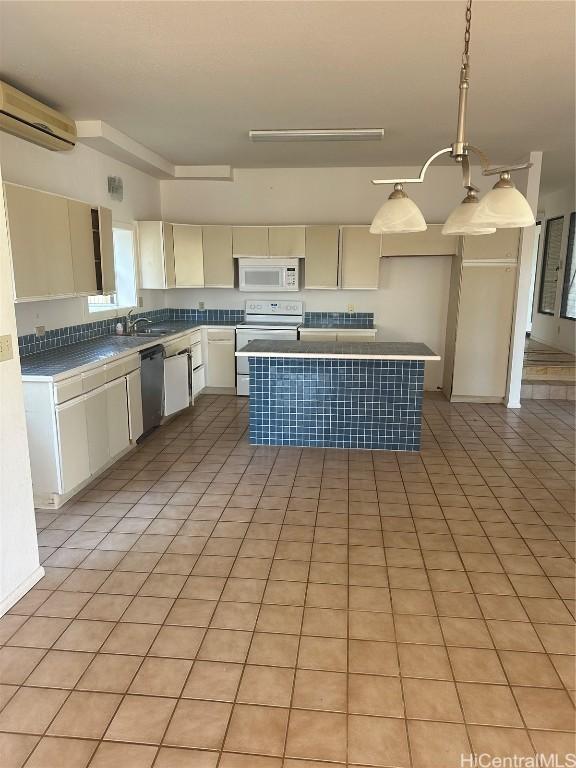 kitchen with white appliances, a wall mounted AC, pendant lighting, light tile patterned floors, and a center island