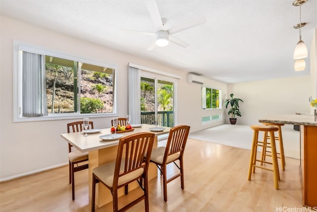 dining room with a textured ceiling, light hardwood / wood-style flooring, a wall unit AC, and ceiling fan