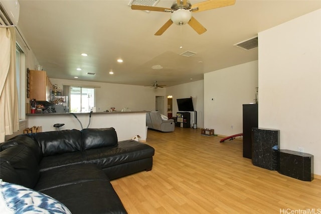 living room with light wood-type flooring, an AC wall unit, and ceiling fan