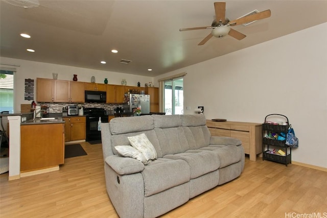 living room with ceiling fan, a healthy amount of sunlight, and light wood-type flooring