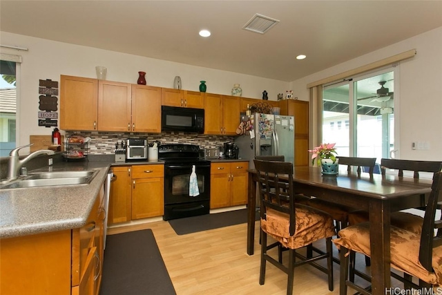 kitchen featuring black appliances, sink, decorative backsplash, ceiling fan, and light wood-type flooring