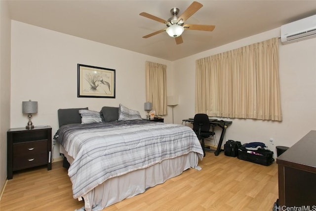 bedroom featuring a wall mounted air conditioner, light wood-type flooring, and ceiling fan