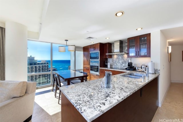 kitchen with stainless steel appliances, hanging light fixtures, wall chimney range hood, tasteful backsplash, and kitchen peninsula