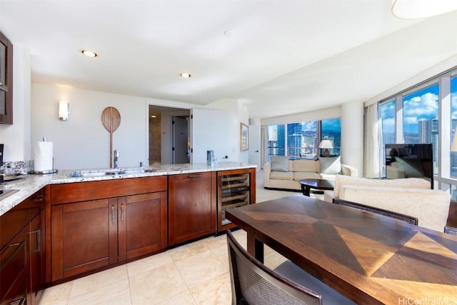 kitchen featuring light stone counters, sink, light tile patterned floors, and beverage cooler