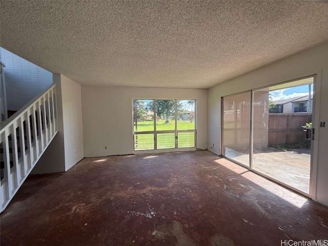 unfurnished living room featuring concrete flooring, a textured ceiling, and a wealth of natural light