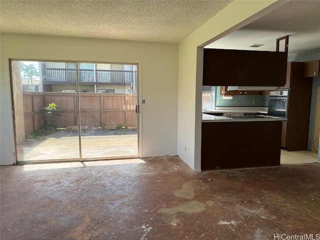 kitchen featuring backsplash, oven, a textured ceiling, dark brown cabinets, and stovetop