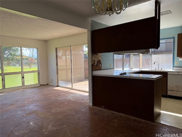 kitchen featuring kitchen peninsula, black electric cooktop, sink, dishwasher, and a chandelier