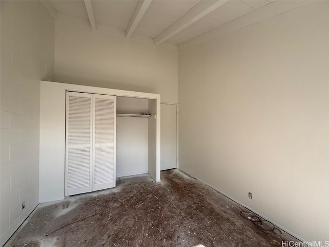 unfurnished bedroom featuring beam ceiling and a closet