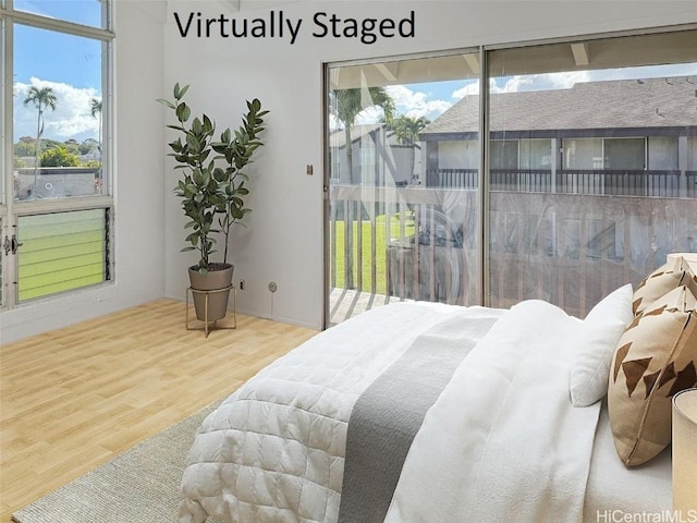 bedroom with multiple windows, wood-type flooring, and access to exterior