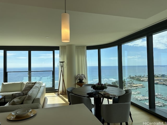 dining area featuring a wall of windows, a water view, a wealth of natural light, and light hardwood / wood-style floors