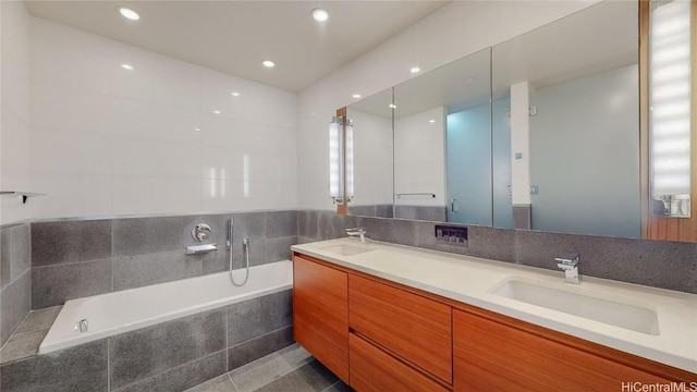 bathroom featuring tile patterned floors, a relaxing tiled tub, and vanity