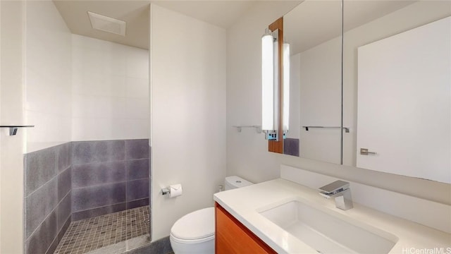 bathroom with vanity, toilet, and a tile shower