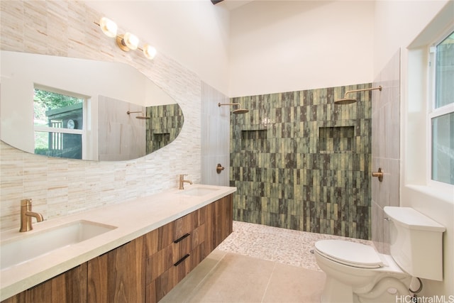 bathroom featuring backsplash, tile patterned floors, a tile shower, vanity, and toilet