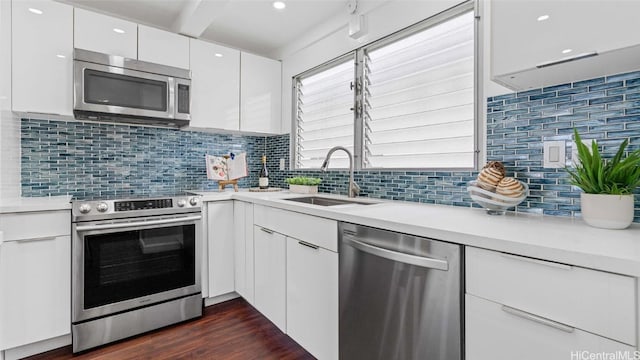 kitchen featuring appliances with stainless steel finishes, a healthy amount of sunlight, sink, dark hardwood / wood-style floors, and white cabinetry