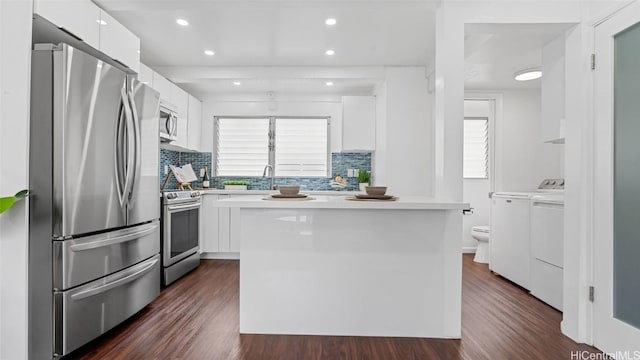 kitchen featuring backsplash, white cabinets, dark hardwood / wood-style floors, appliances with stainless steel finishes, and washing machine and clothes dryer