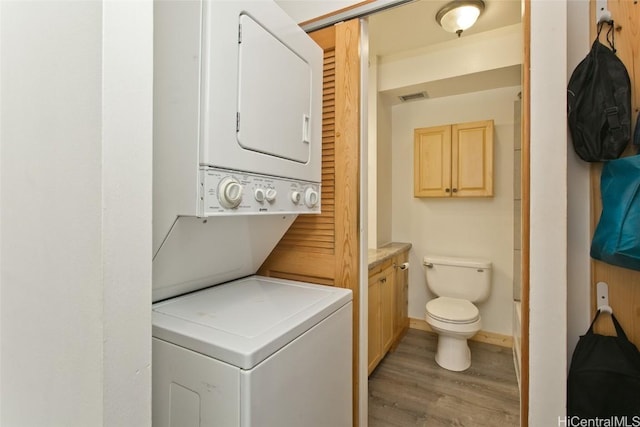 laundry area featuring stacked washer and dryer and light hardwood / wood-style flooring