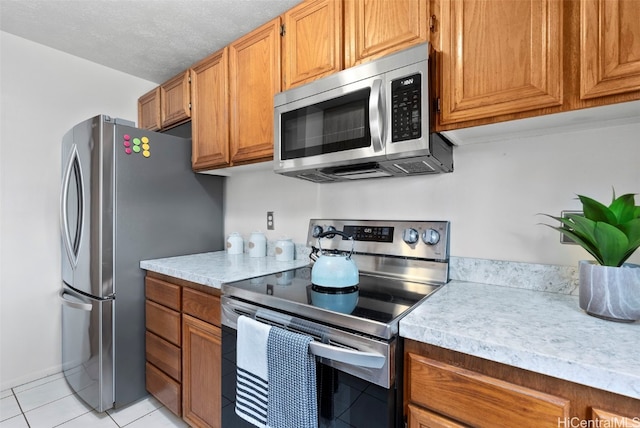 kitchen with a textured ceiling, stainless steel appliances, and light tile patterned flooring