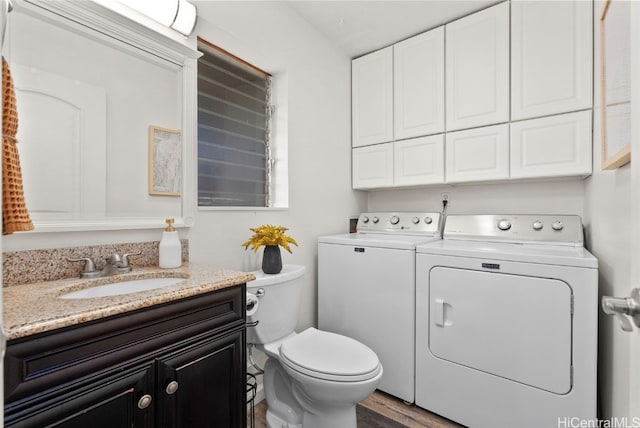 bathroom with vanity, washing machine and clothes dryer, hardwood / wood-style floors, and toilet