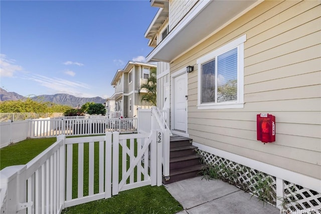 view of exterior entry featuring a mountain view and a lawn