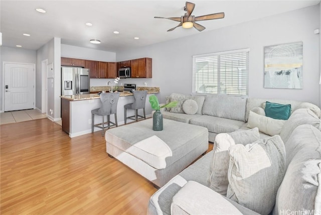 living room with ceiling fan, sink, and light hardwood / wood-style floors