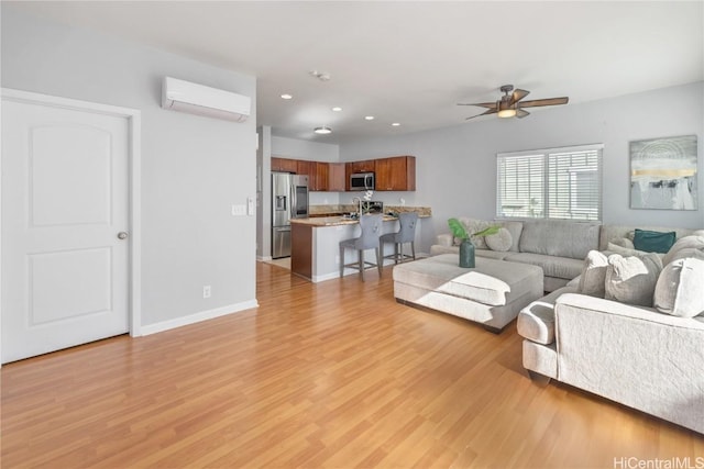 living room with a wall mounted air conditioner, light hardwood / wood-style floors, and ceiling fan