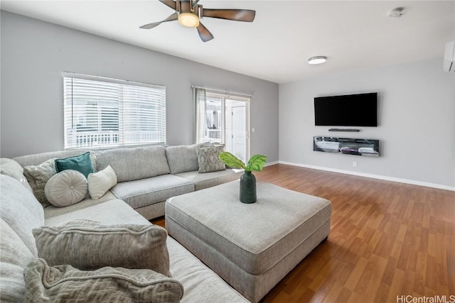 living room with hardwood / wood-style flooring, a wall mounted AC, and ceiling fan