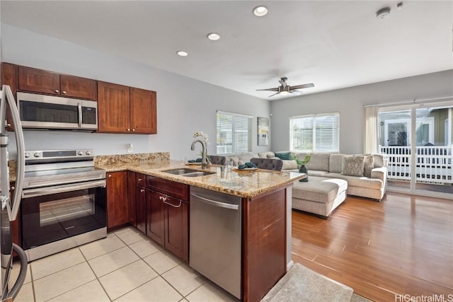 kitchen featuring light stone counters, stainless steel appliances, kitchen peninsula, and sink