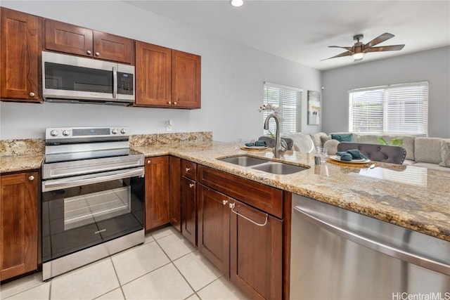 kitchen featuring sink, stainless steel appliances, light stone counters, light tile patterned flooring, and kitchen peninsula