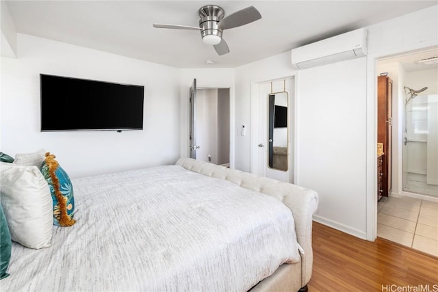 bedroom featuring ensuite bathroom, wood-type flooring, a closet, a wall unit AC, and ceiling fan