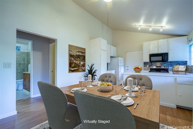 dining room with hardwood / wood-style floors, high vaulted ceiling, and rail lighting