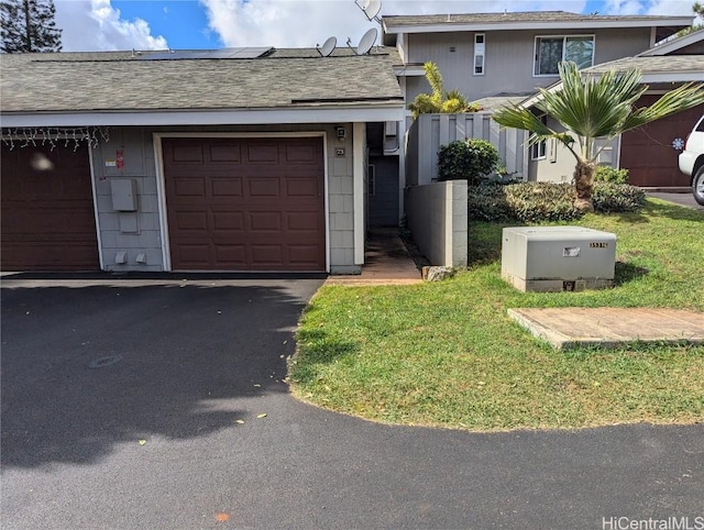 view of front facade with a garage, a front yard, roof with shingles, and driveway