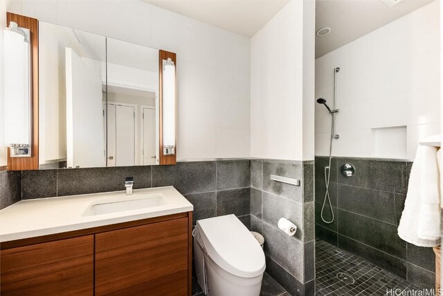 bathroom featuring tiled shower, vanity, toilet, and tile walls