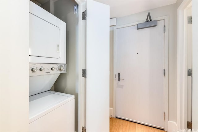 clothes washing area with light hardwood / wood-style floors and stacked washer and dryer