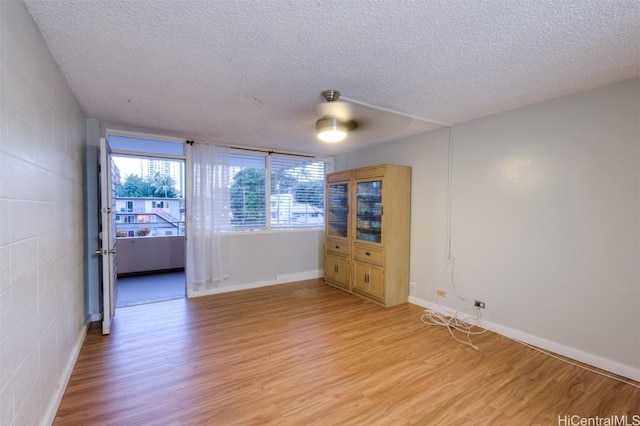 empty room with ceiling fan, light hardwood / wood-style floors, and a textured ceiling