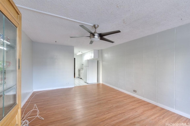 unfurnished room featuring ceiling fan, light wood-type flooring, and a textured ceiling