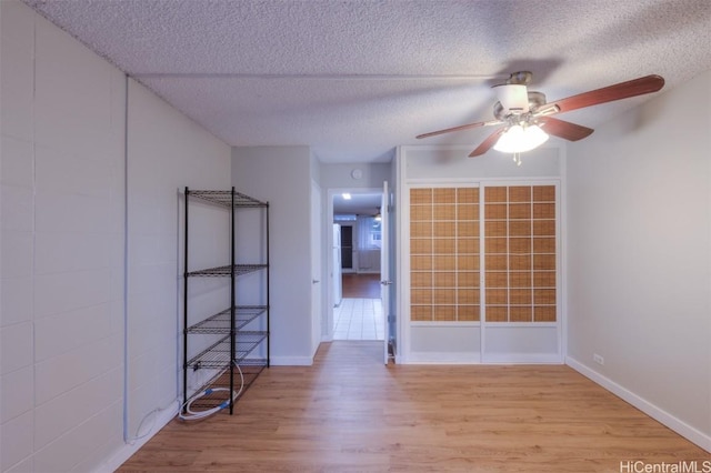 empty room with a textured ceiling, light hardwood / wood-style floors, and ceiling fan