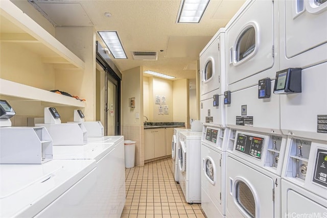 laundry area featuring light tile patterned floors, a textured ceiling, washer and clothes dryer, and stacked washer and clothes dryer